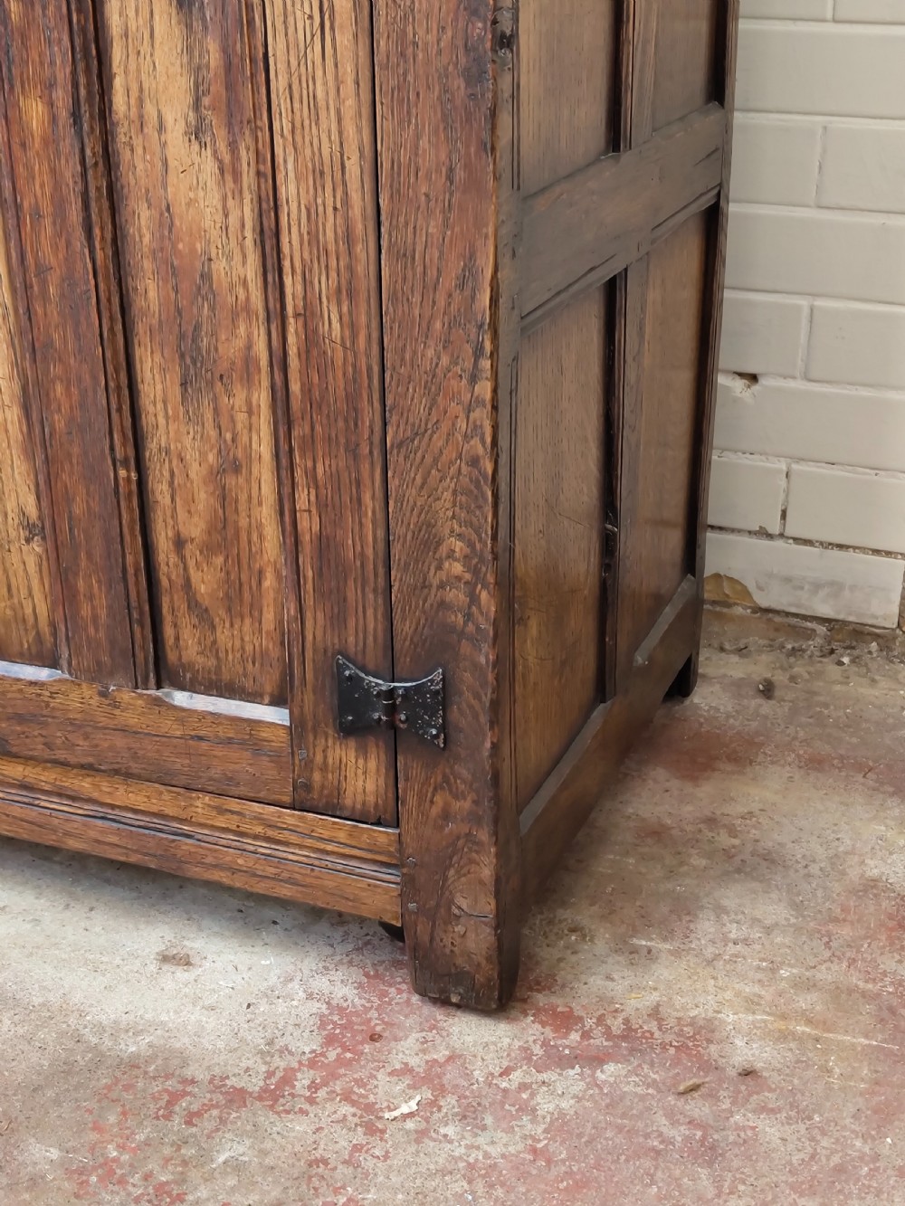A tall solid oak double wardrobe featuring carved linenfold upper panels and black iron strap hinges. View III