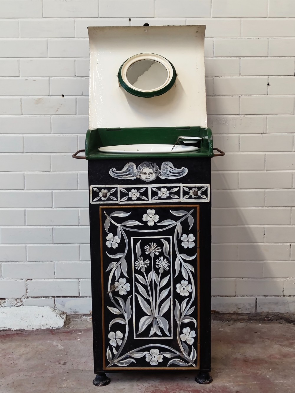 A hand-painted black and green metal toleware washstand with an open lid revealing a circular mirror and a fitted ceramic washbasin. View XIX