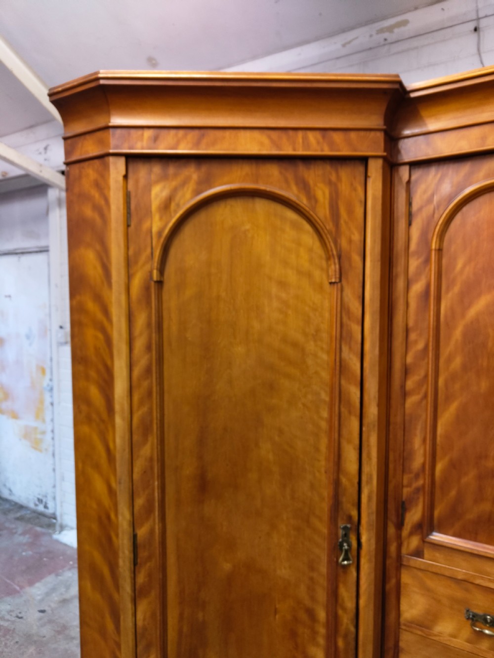 Victorian satin birch corner compactum wardrobe featuring arched panelled doors, brass hardware, and a integrated chest of drawers. View V