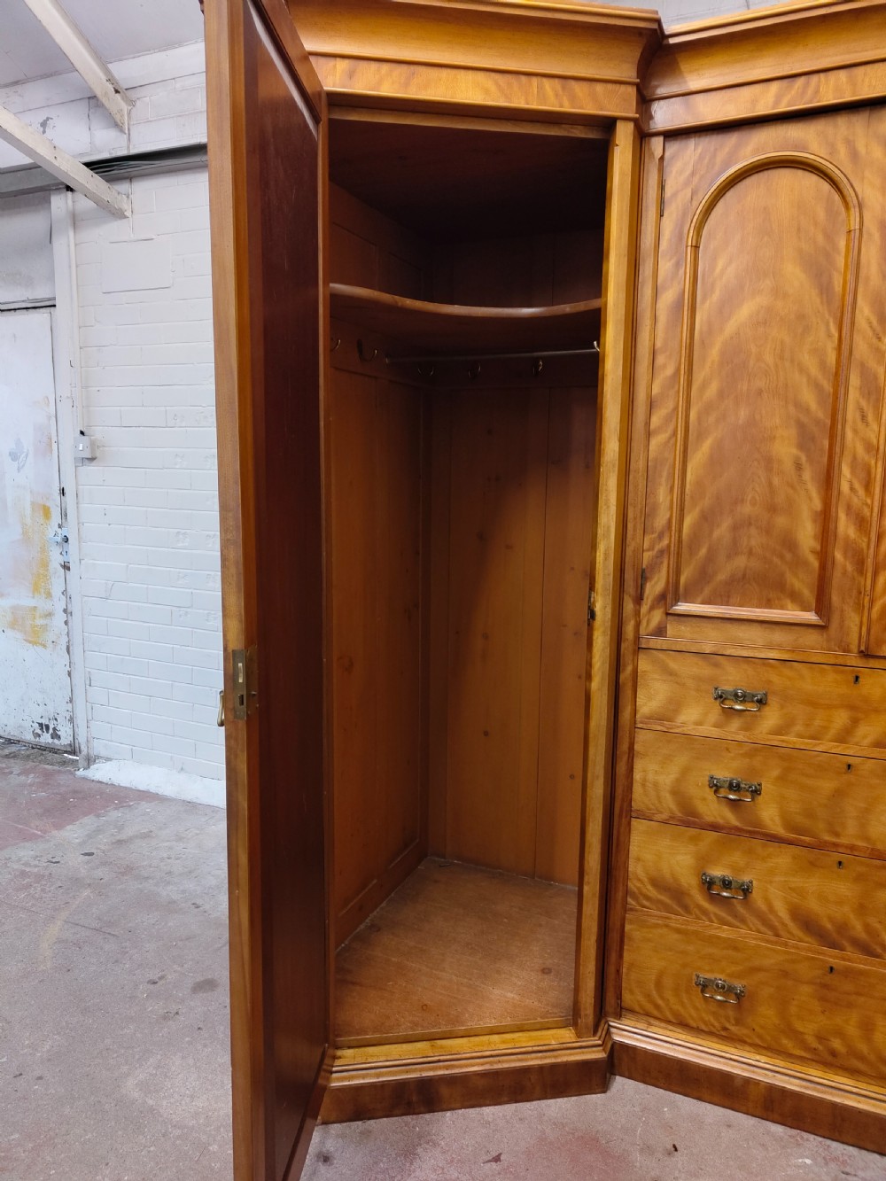 Victorian satin birch corner compactum wardrobe featuring arched panelled doors, brass hardware, and a integrated chest of drawers. View VI
