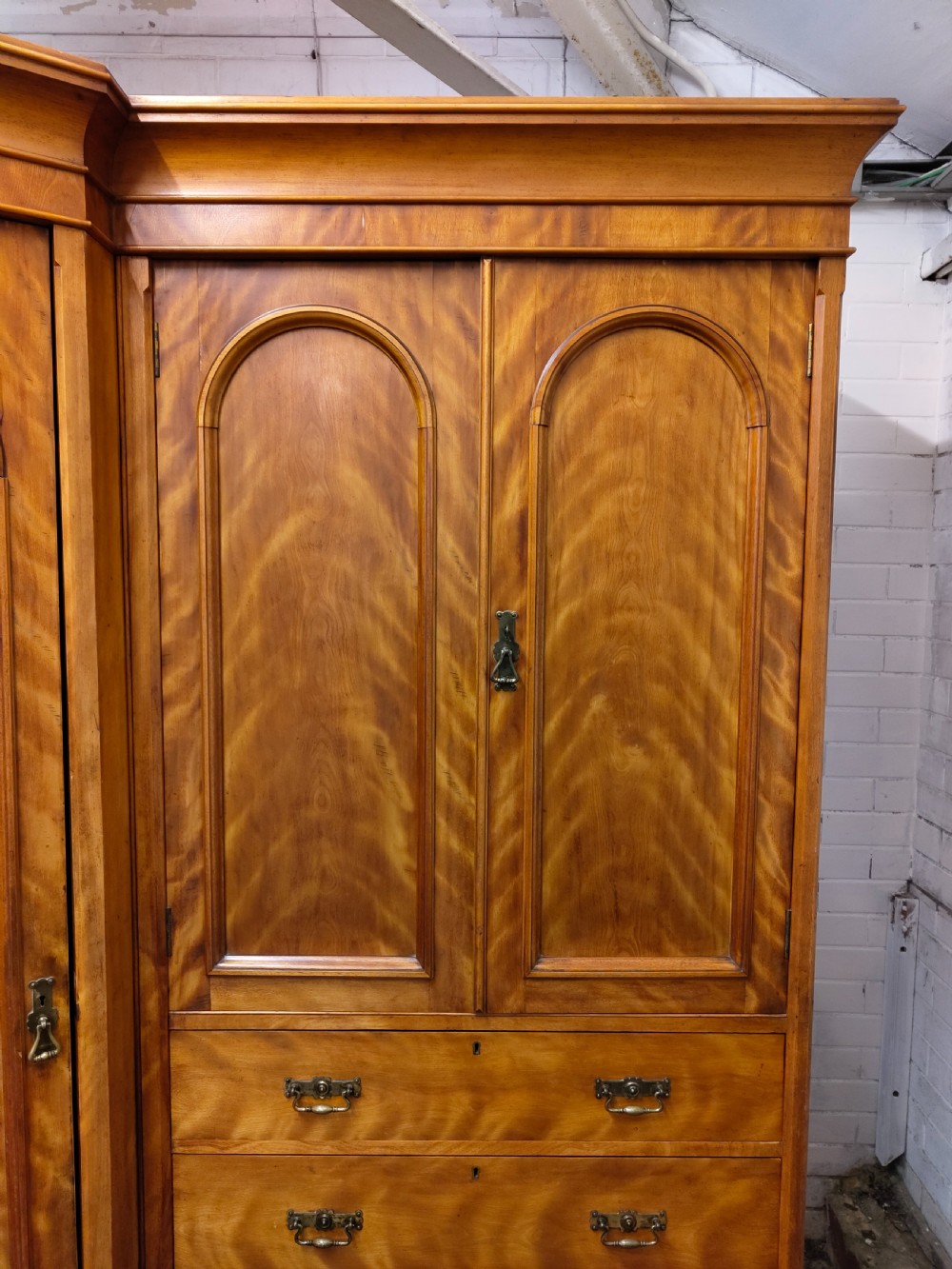 Victorian satin birch corner compactum wardrobe featuring arched panelled doors, brass hardware, and a integrated chest of drawers. View XVIII
