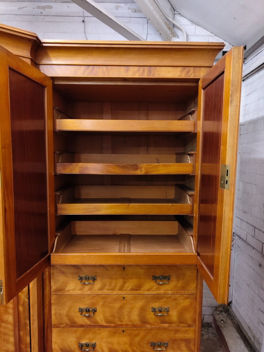 Victorian satin birch corner compactum wardrobe featuring arched panelled doors, brass hardware, and a integrated chest of drawers. View XXIII