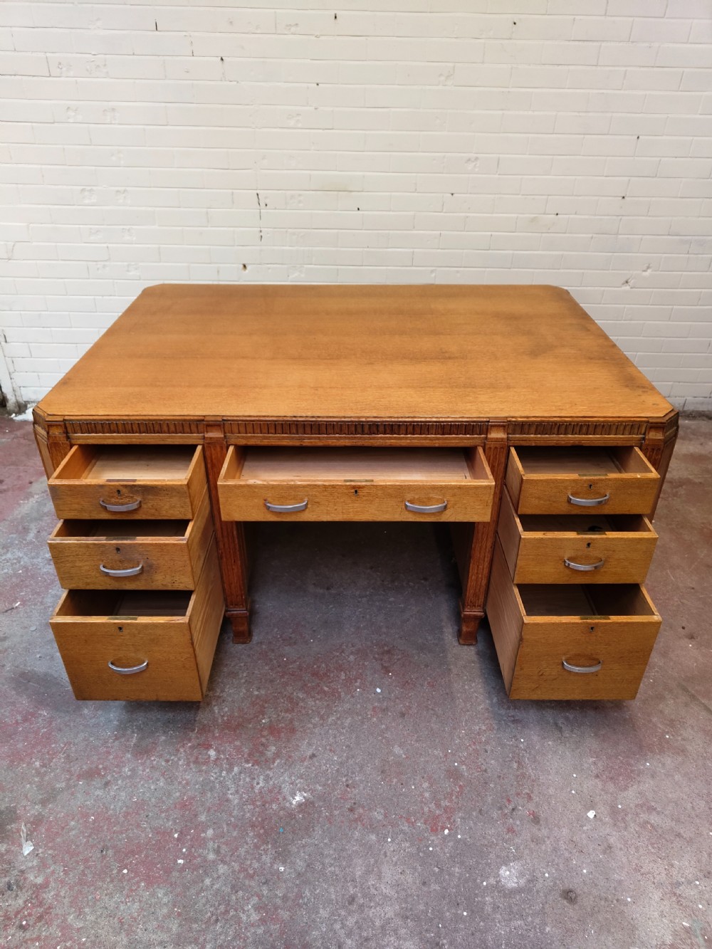 A large golden oak Art Deco partners desk featuring reeded corner details, dual pedestals with drawers, and metal pull handles. View II