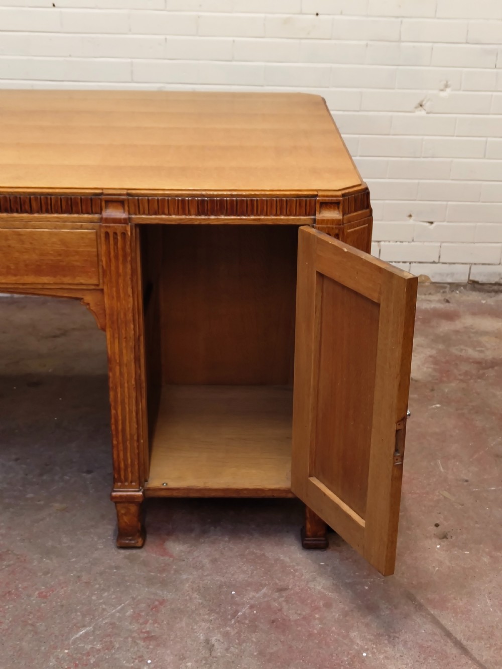 A large golden oak Art Deco partners desk featuring reeded corner details, dual pedestals with drawers, and metal pull handles. View V