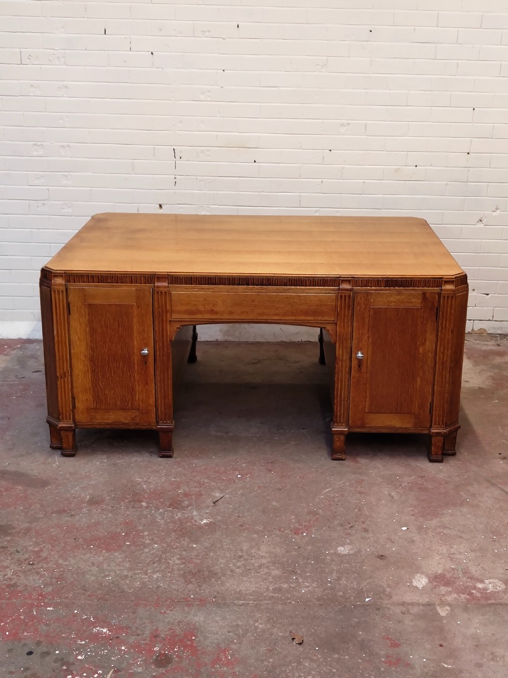 A large golden oak Art Deco partners desk featuring reeded corner details, dual pedestals with drawers, and metal pull handles. View VIII