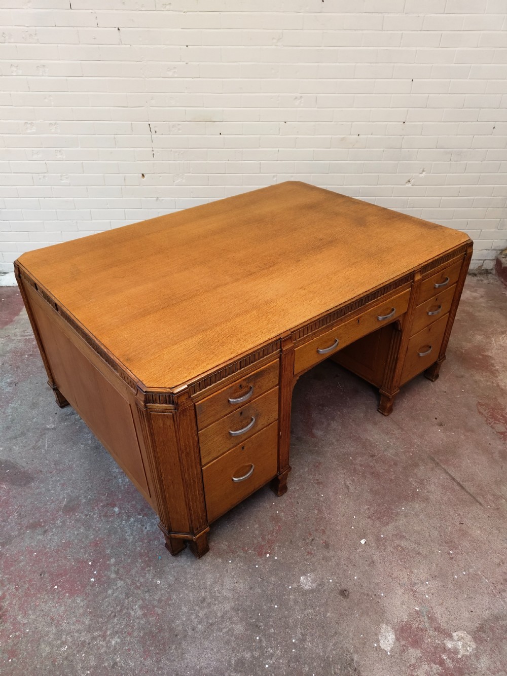 A large golden oak Art Deco partners desk featuring reeded corner details, dual pedestals with drawers, and metal pull handles. View XIII