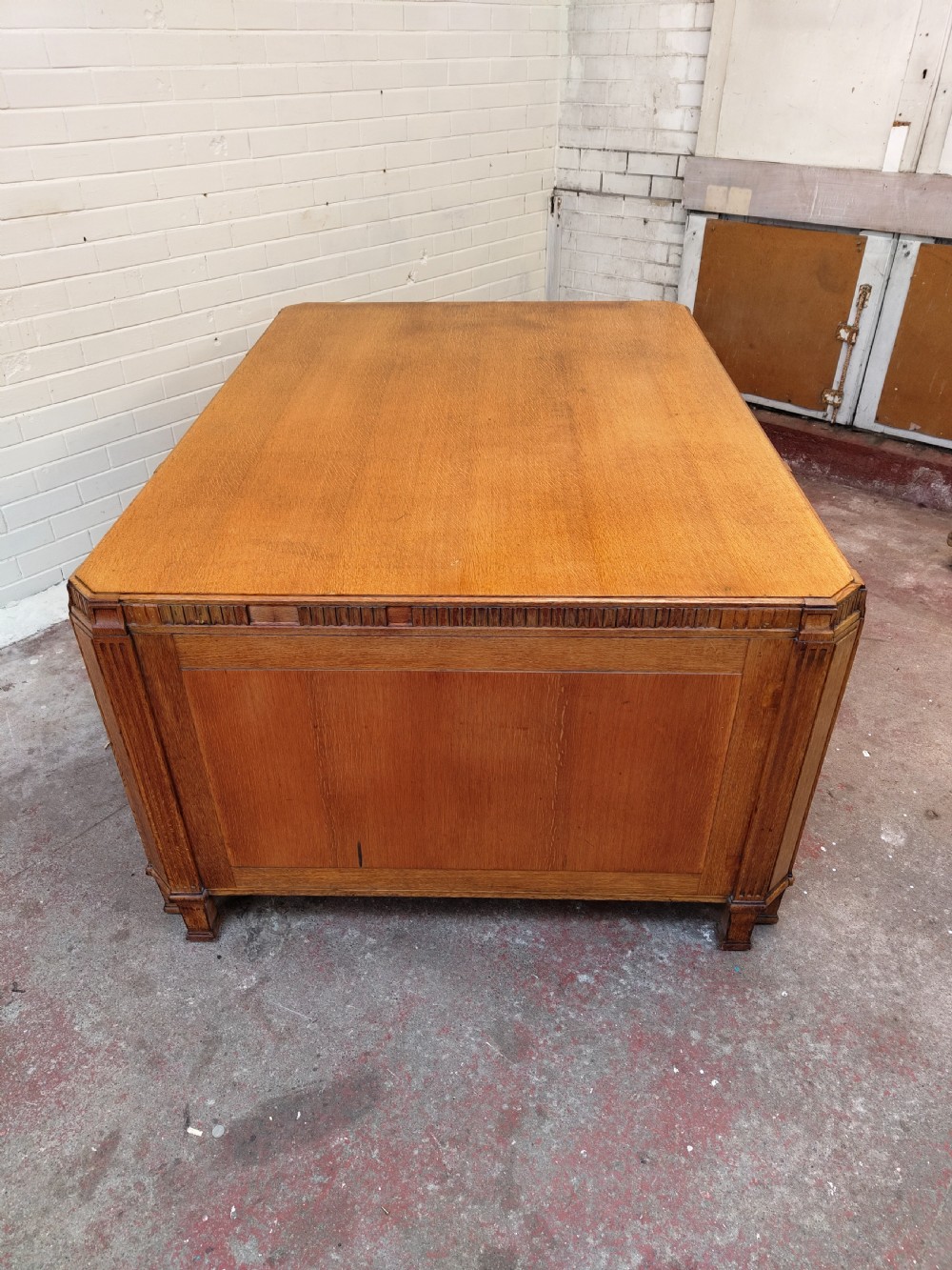 A large golden oak Art Deco partners desk featuring reeded corner details, dual pedestals with drawers, and metal pull handles. View XIV