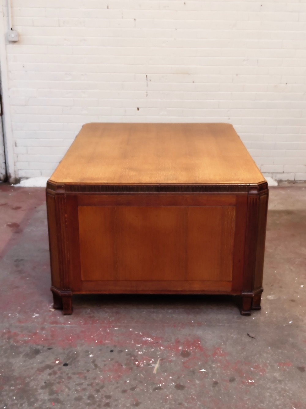 A large golden oak Art Deco partners desk featuring reeded corner details, dual pedestals with drawers, and metal pull handles. View XVI