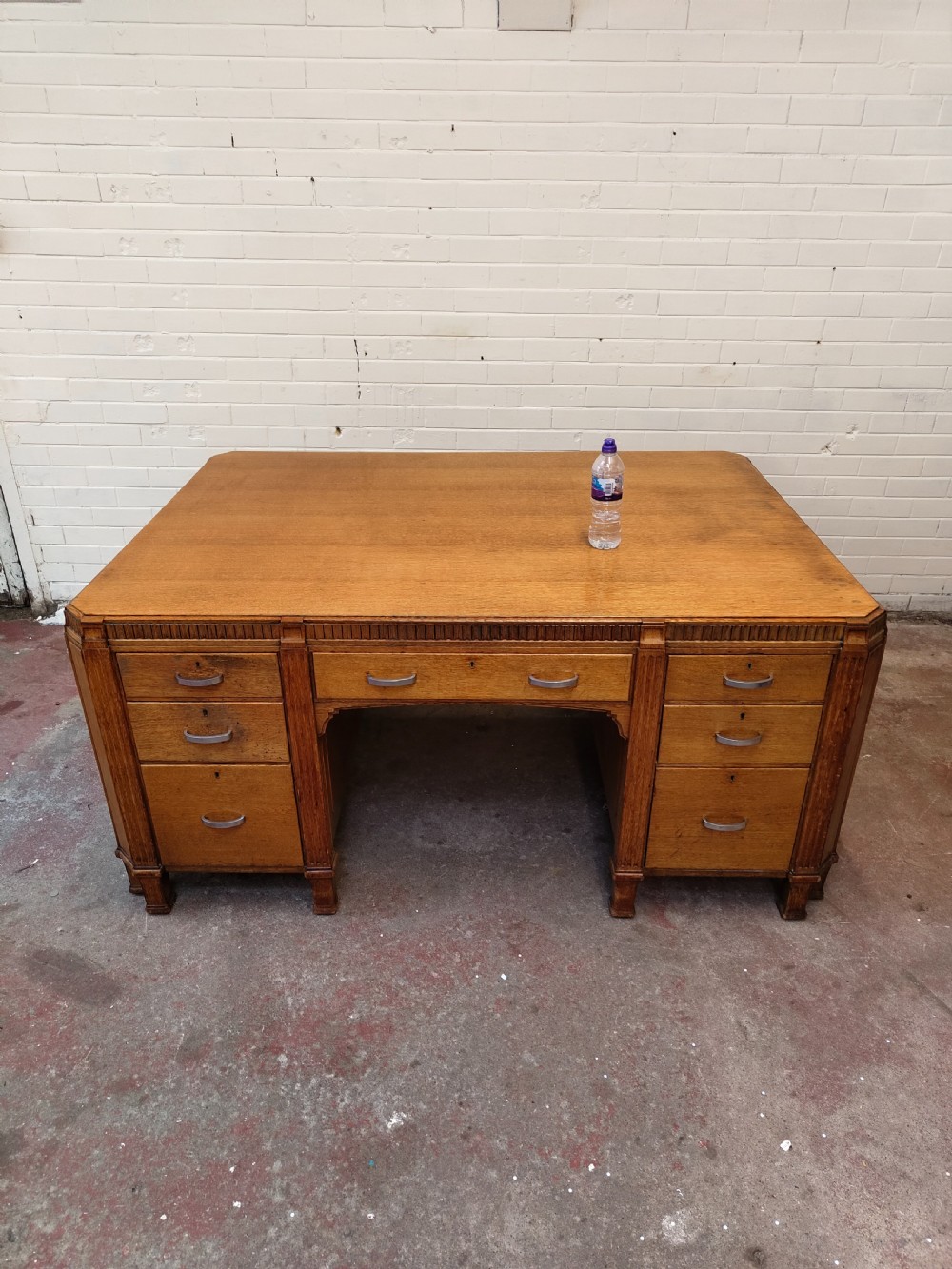 A large golden oak Art Deco partners desk featuring reeded corner details, dual pedestals with drawers, and metal pull handles. View XXII