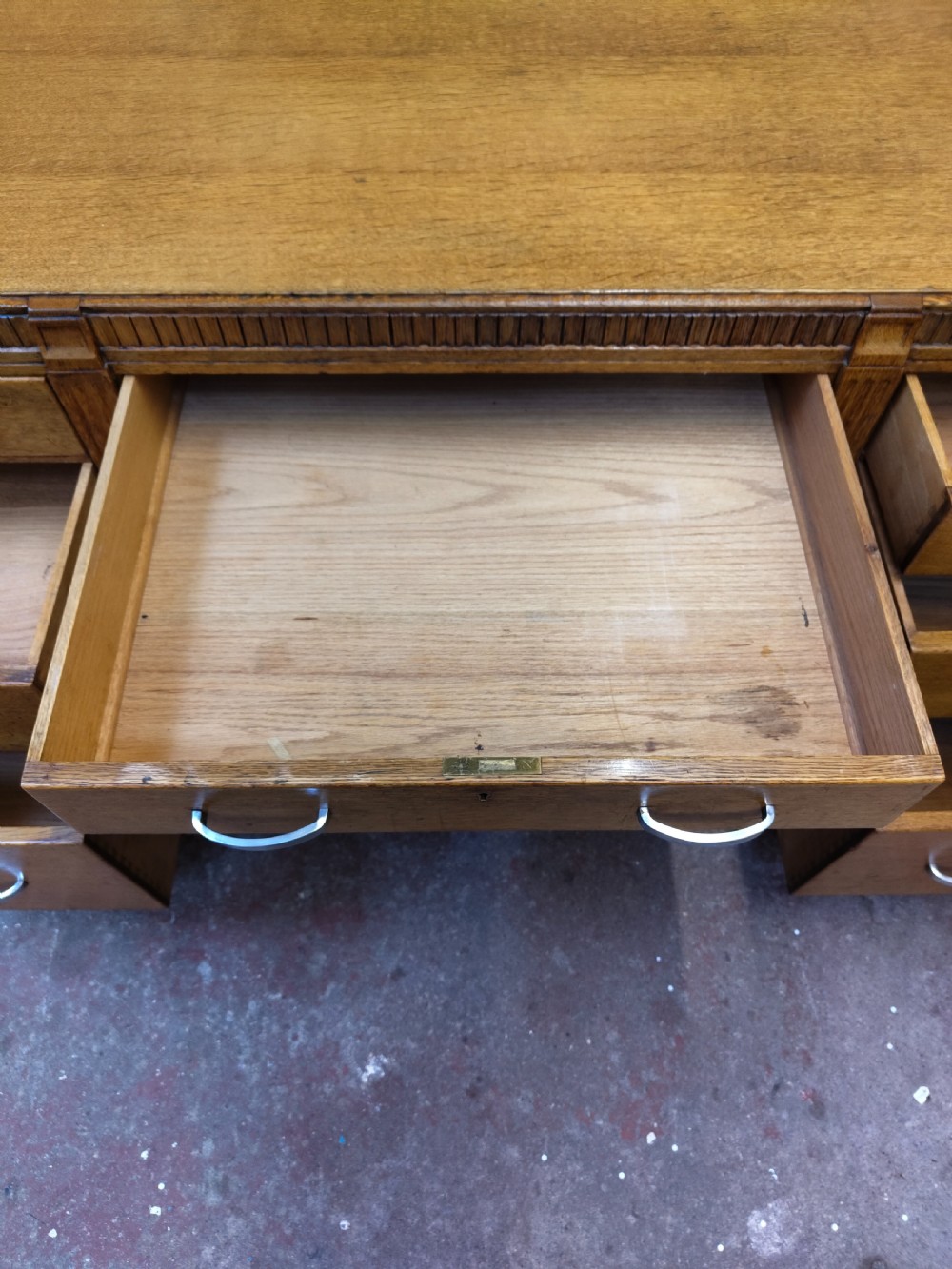 A large golden oak Art Deco partners desk featuring reeded corner details, dual pedestals with drawers, and metal pull handles. View XXIV