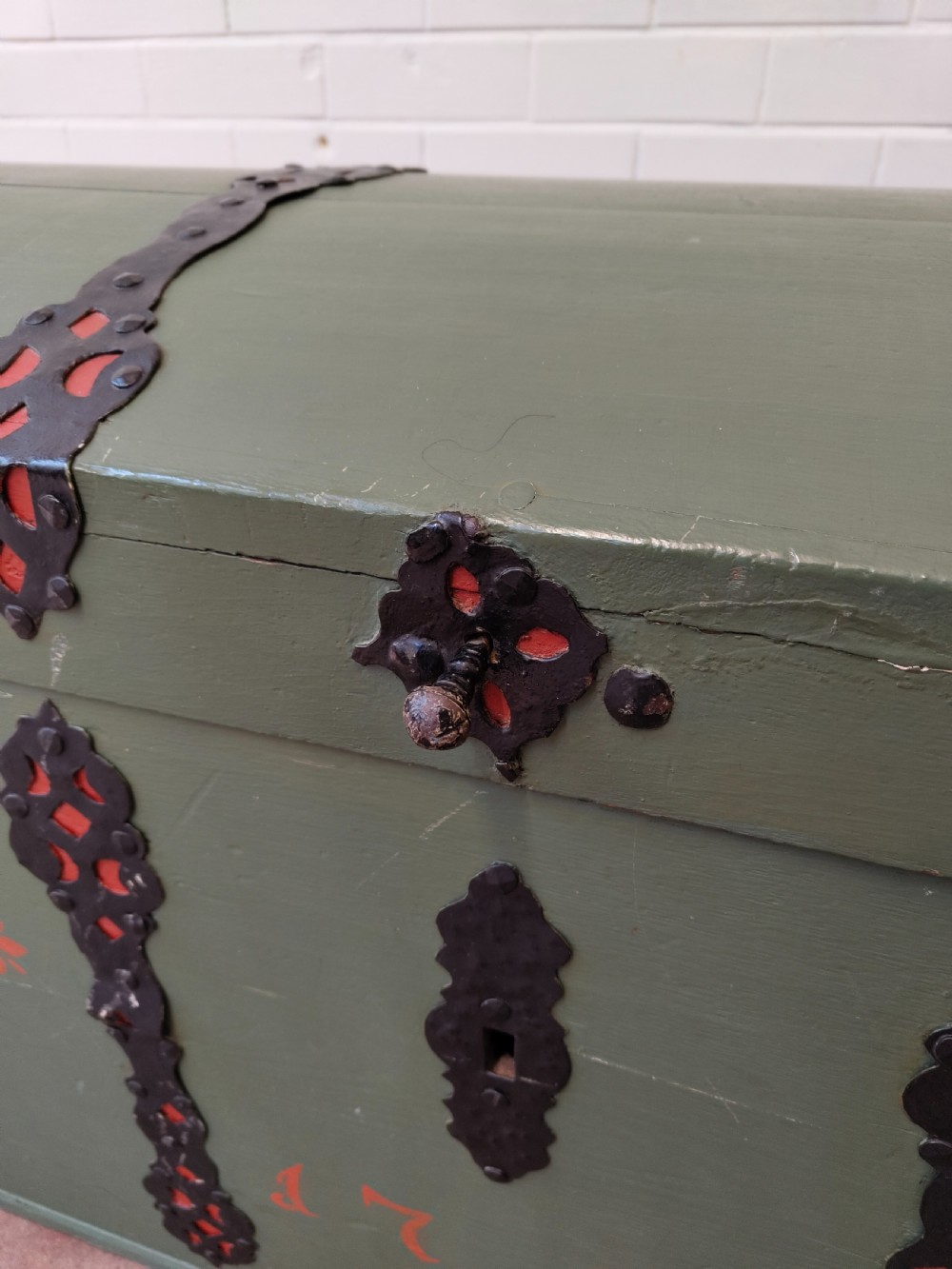A green painted wooden dome top trunk featuring black decorative iron straps, red painted initials AH, and the date 1709. View II