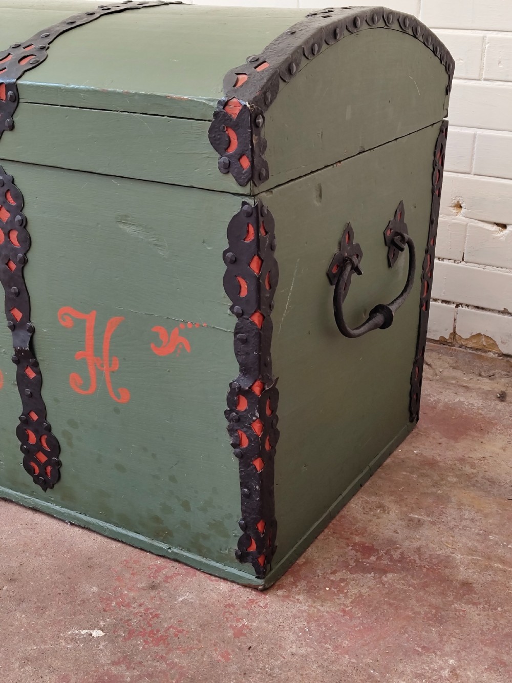 A green painted wooden dome top trunk featuring black decorative iron straps, red painted initials AH, and the date 1709. View IV