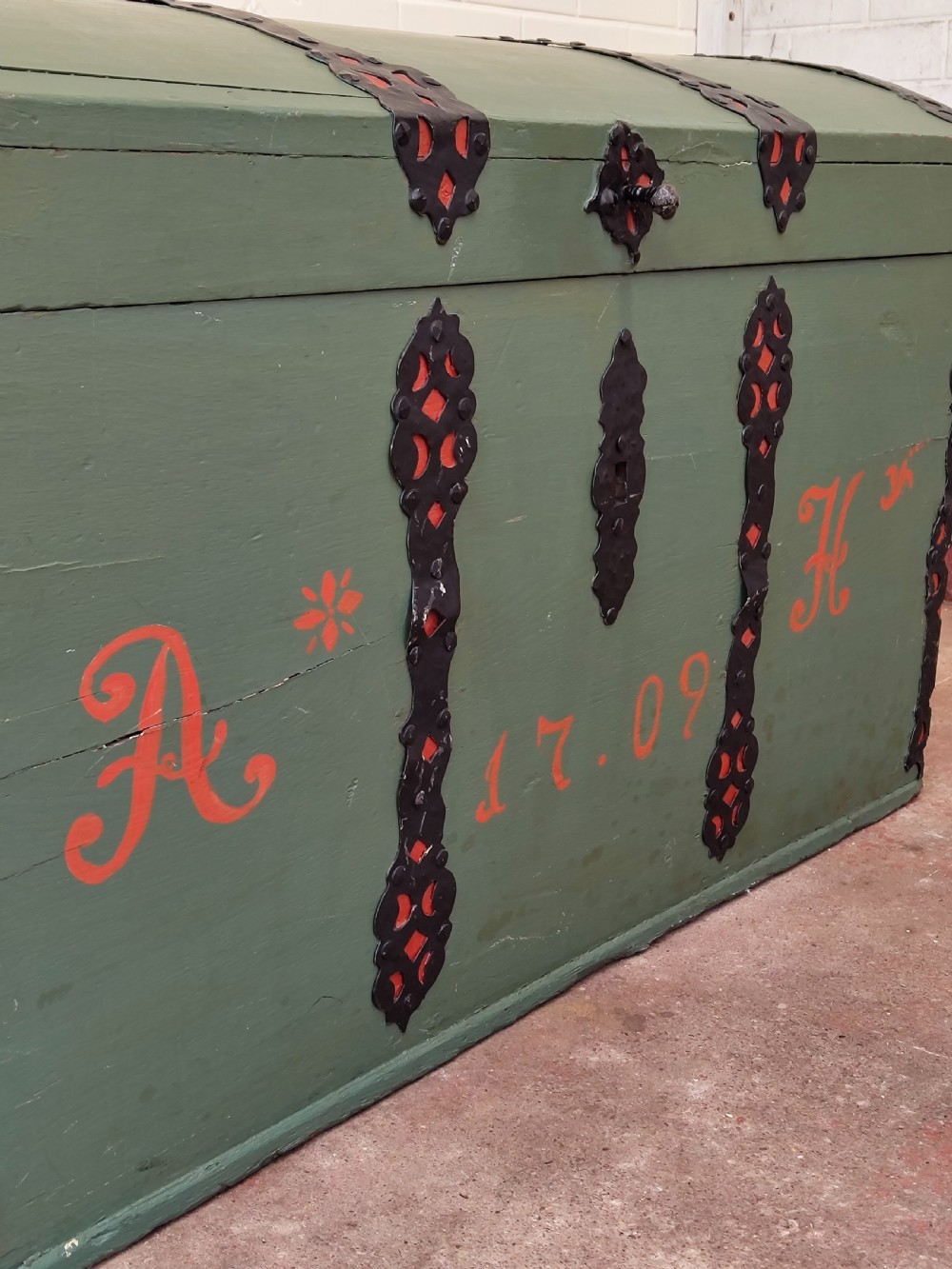 A green painted wooden dome top trunk featuring black decorative iron straps, red painted initials AH, and the date 1709. View VI