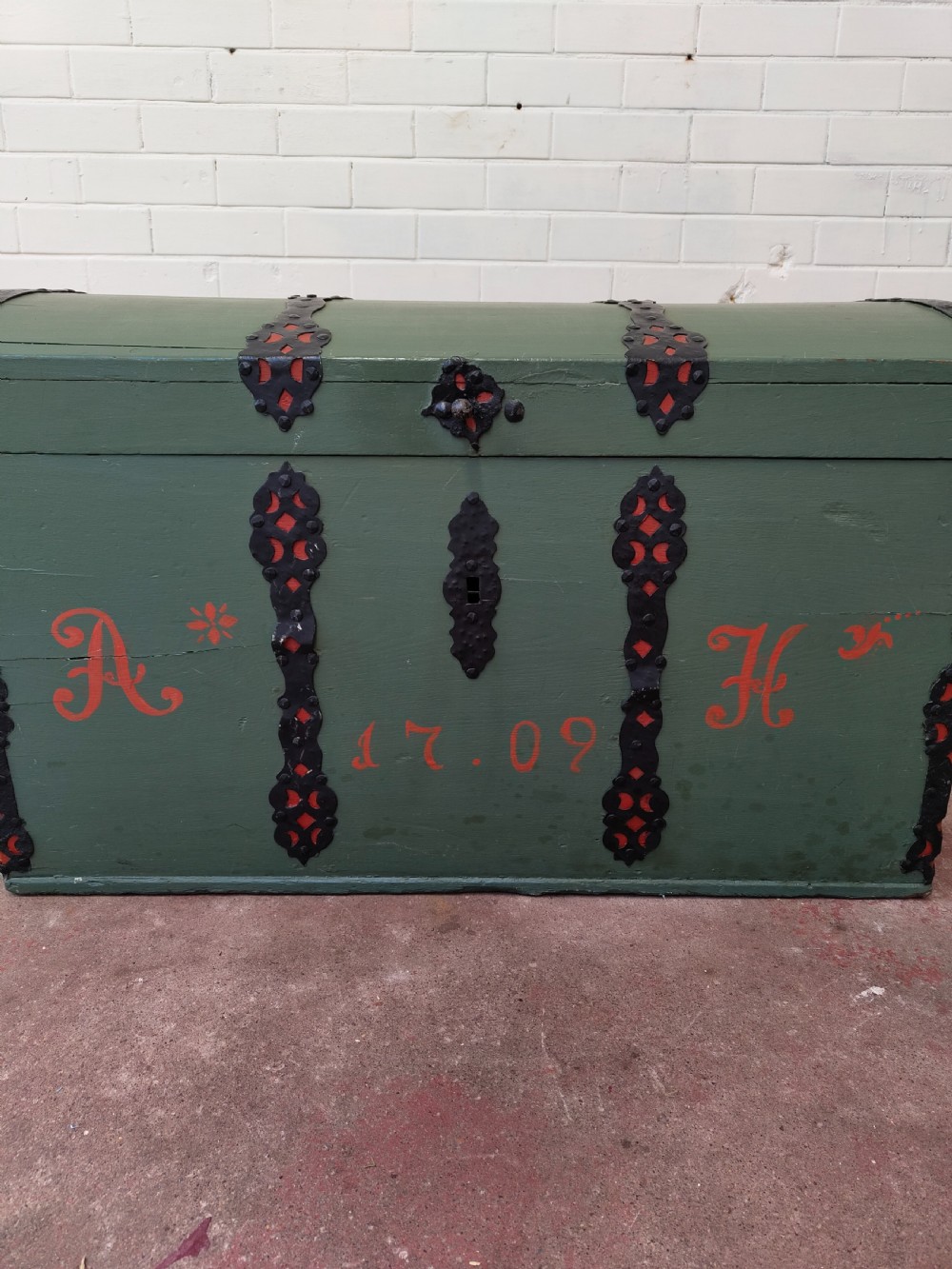 A green painted wooden dome top trunk featuring black decorative iron straps, red painted initials AH, and the date 1709. View VIII