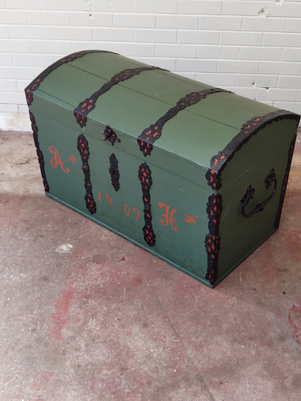 A green painted wooden dome top trunk featuring black decorative iron straps, red painted initials AH, and the date 1709. View XI