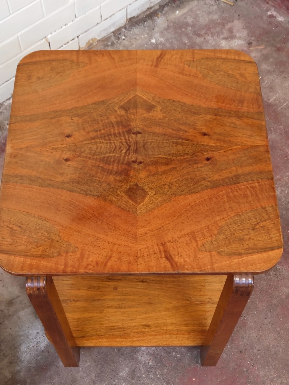 A matching pair of two-tier Art Deco burr walnut bedside tables featuring rounded tops, lower shelves, curved upright legs, and small castor wheels. View VIII