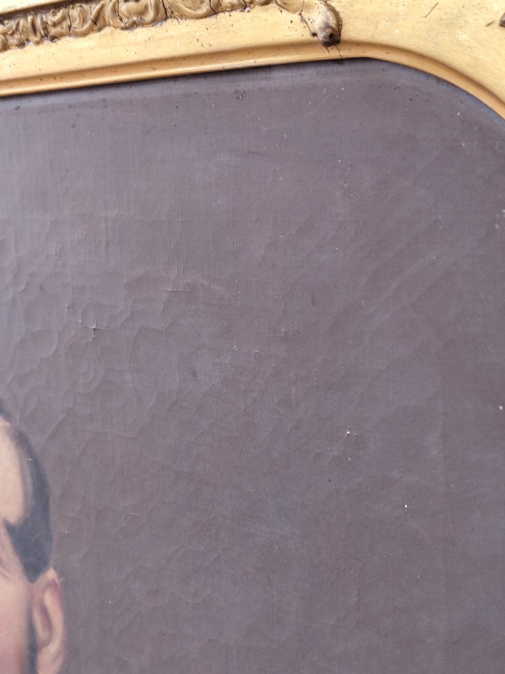 A Victorian oil painting depicting a seated gentleman in a dark suit set inside a large, ornate gilded gesso frame. View VII