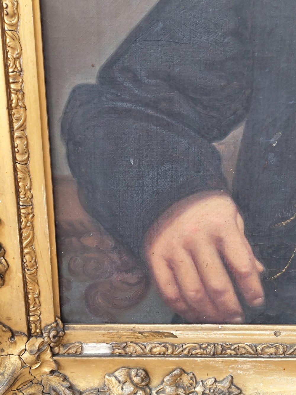 A Victorian oil painting depicting a seated gentleman in a dark suit set inside a large, ornate gilded gesso frame. View XV