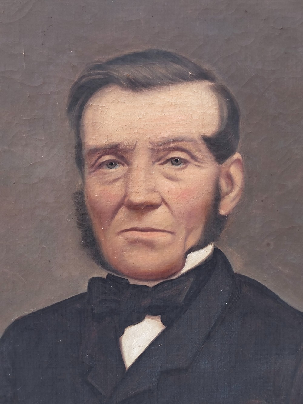 A Victorian oil painting depicting a seated gentleman in a dark suit set inside a large, ornate gilded gesso frame. View XVI