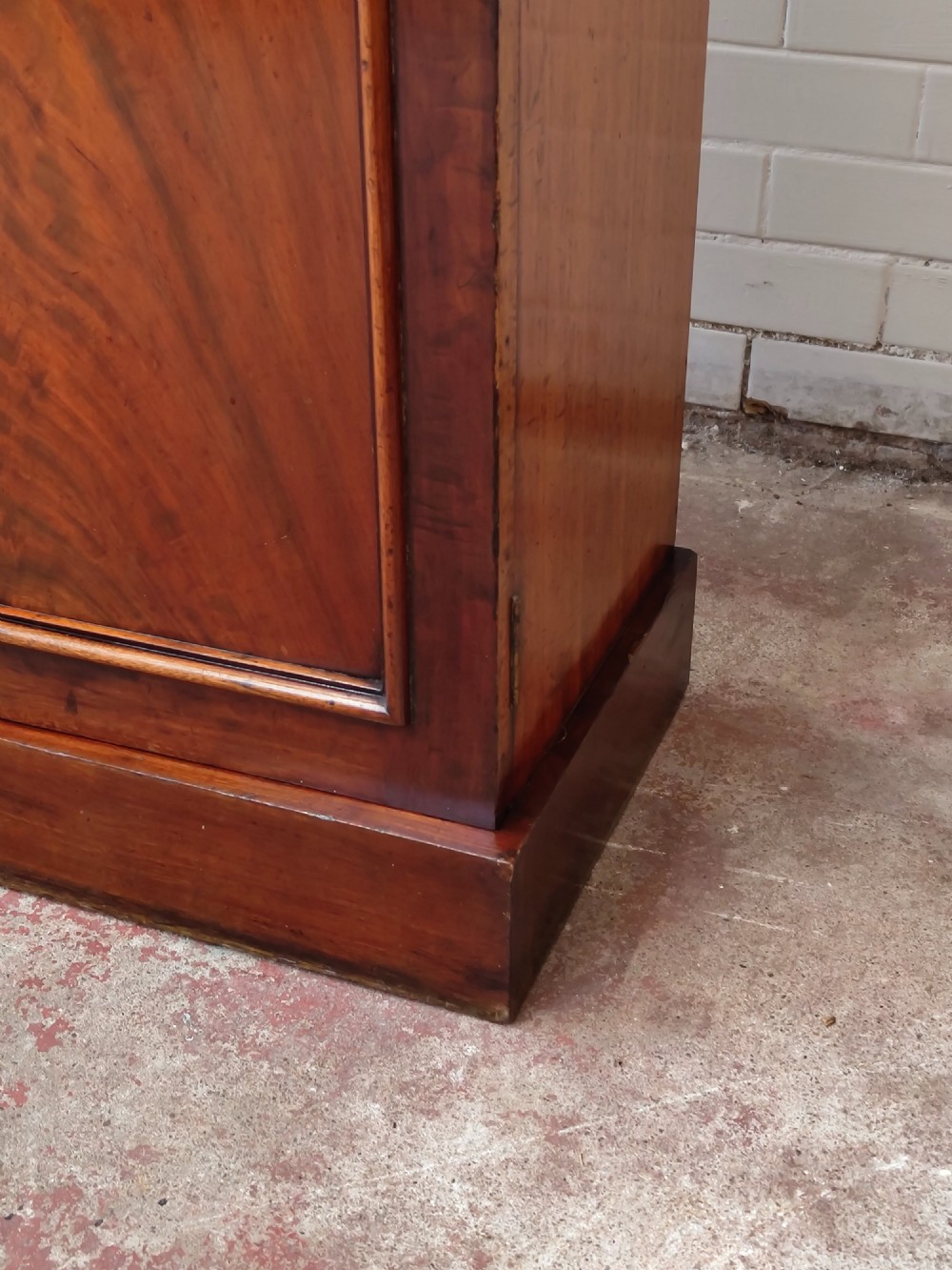 A tall Victorian mahogany bookcase featuring a glazed upper display cabinet with adjustable shelves over a lower two-door cupboard with flame mahogany veneer panels. View III