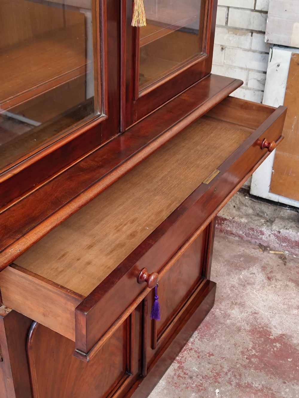 A tall Victorian mahogany bookcase featuring a glazed upper display cabinet with adjustable shelves over a lower two-door cupboard with flame mahogany veneer panels. View XI