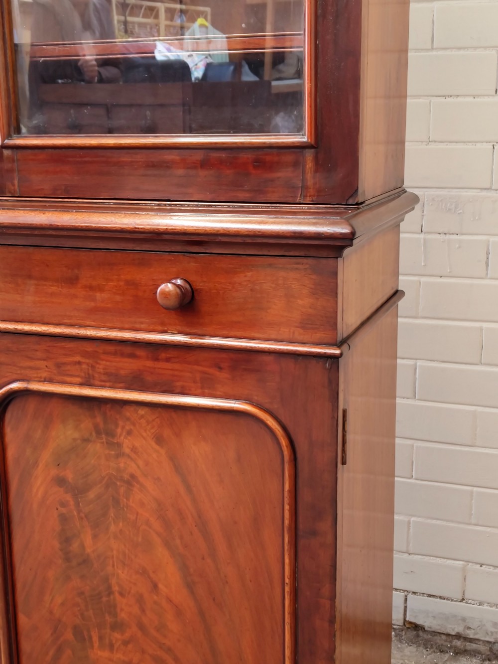 A tall Victorian mahogany bookcase featuring a glazed upper display cabinet with adjustable shelves over a lower two-door cupboard with flame mahogany veneer panels. View XV