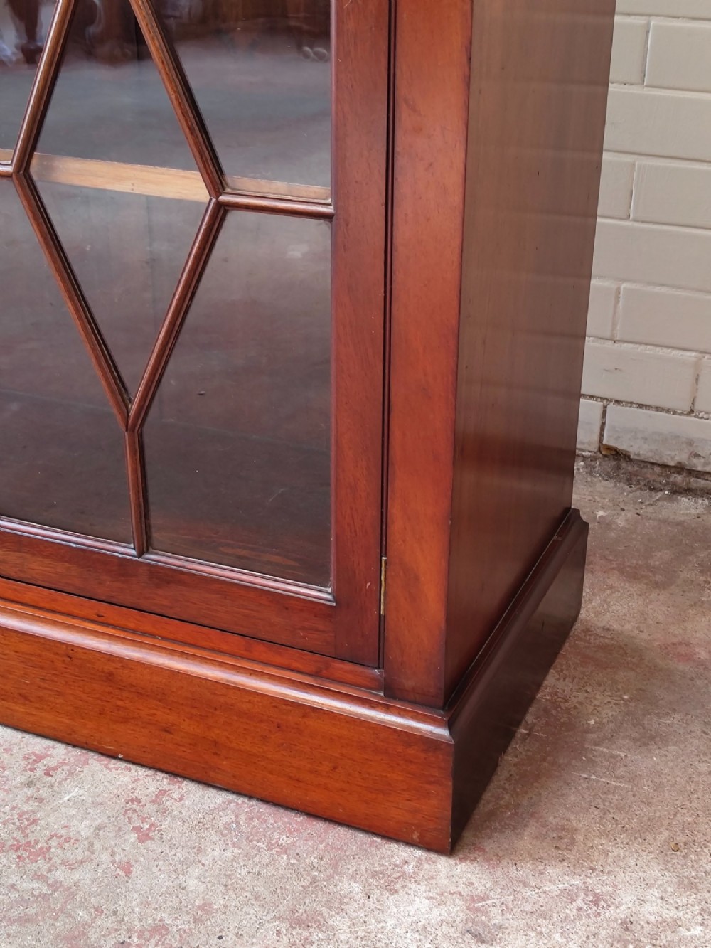 A tall Victorian mahogany bookcase featuring upper and lower double doors with diamond astragal glazed panels and adjustable interior shelves. View II