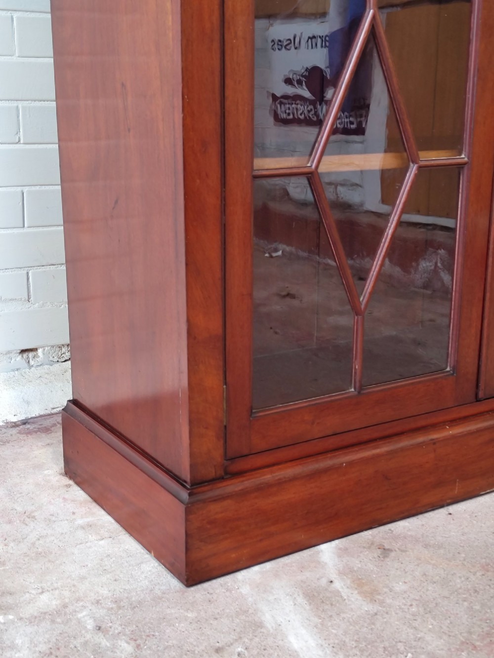 A tall Victorian mahogany bookcase featuring upper and lower double doors with diamond astragal glazed panels and adjustable interior shelves. View III
