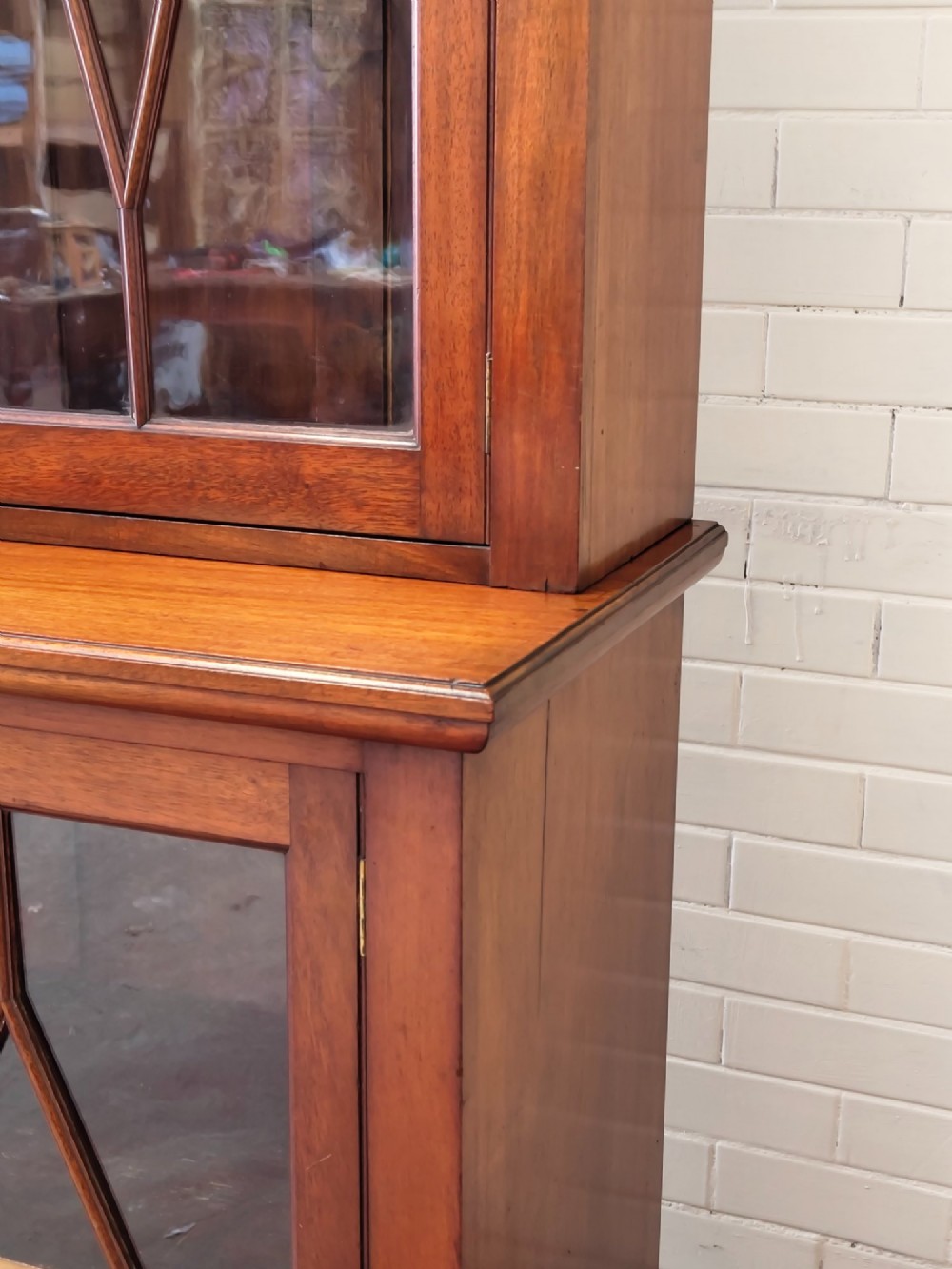A tall Victorian mahogany bookcase featuring upper and lower double doors with diamond astragal glazed panels and adjustable interior shelves. View V