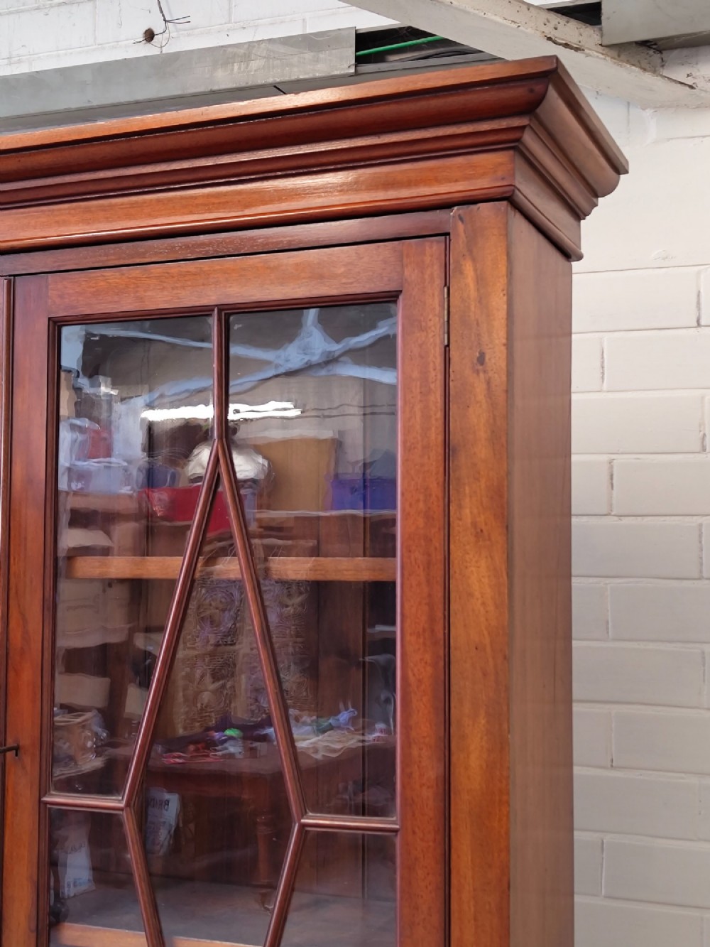 A tall Victorian mahogany bookcase featuring upper and lower double doors with diamond astragal glazed panels and adjustable interior shelves. View VI