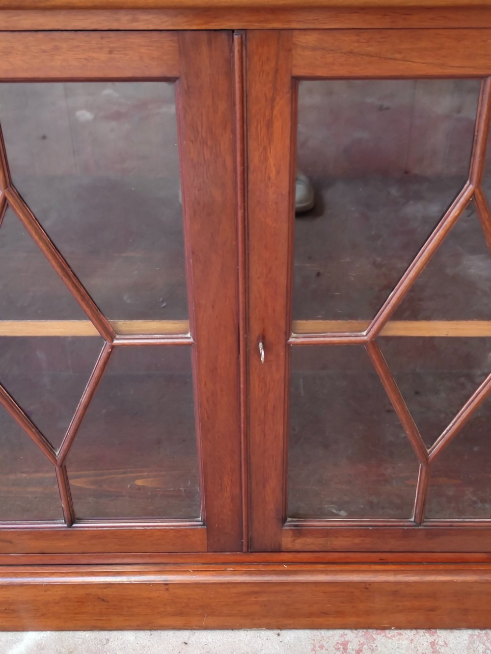 A tall Victorian mahogany bookcase featuring upper and lower double doors with diamond astragal glazed panels and adjustable interior shelves. View VII