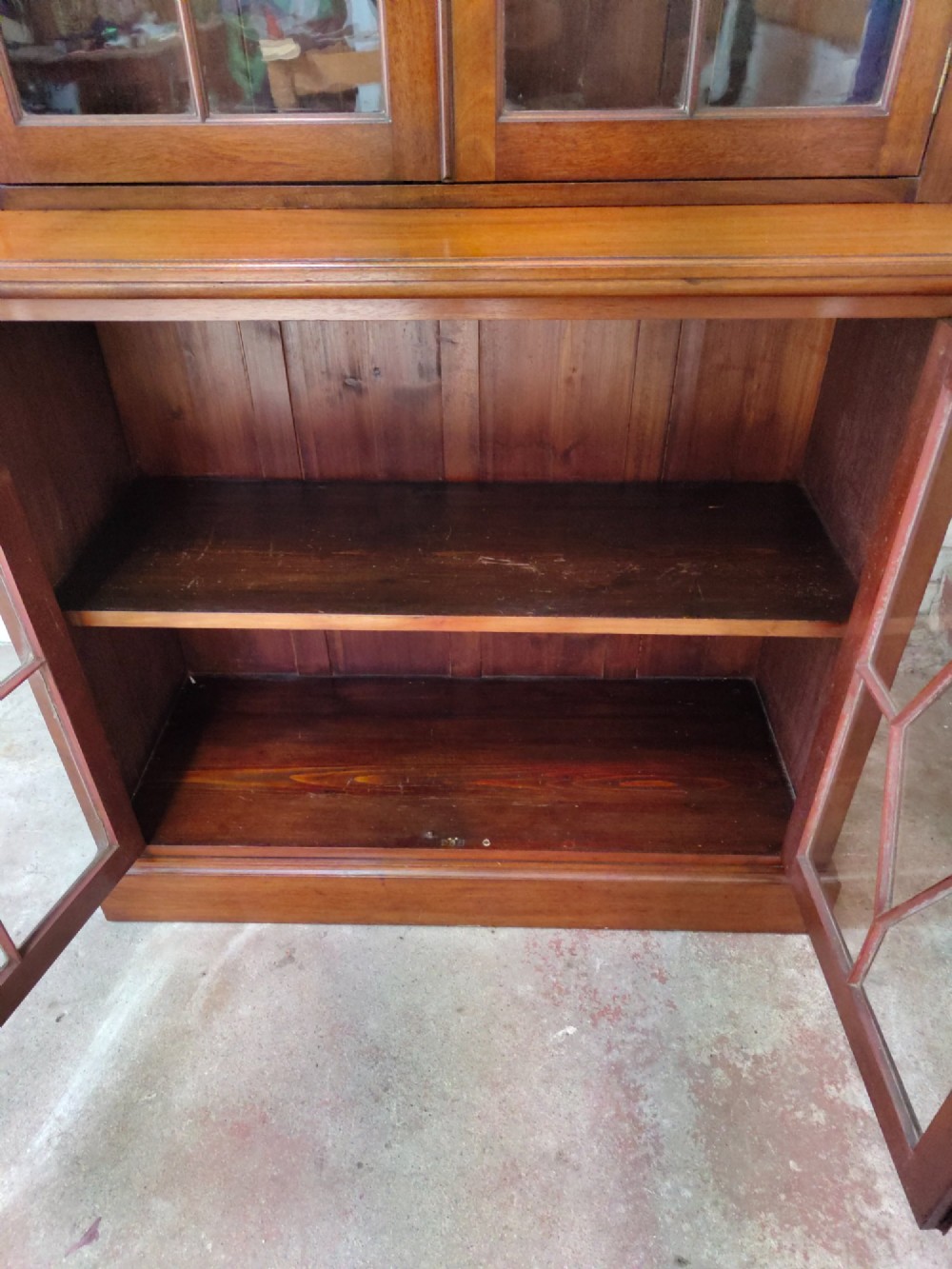 A tall Victorian mahogany bookcase featuring upper and lower double doors with diamond astragal glazed panels and adjustable interior shelves. View VIII