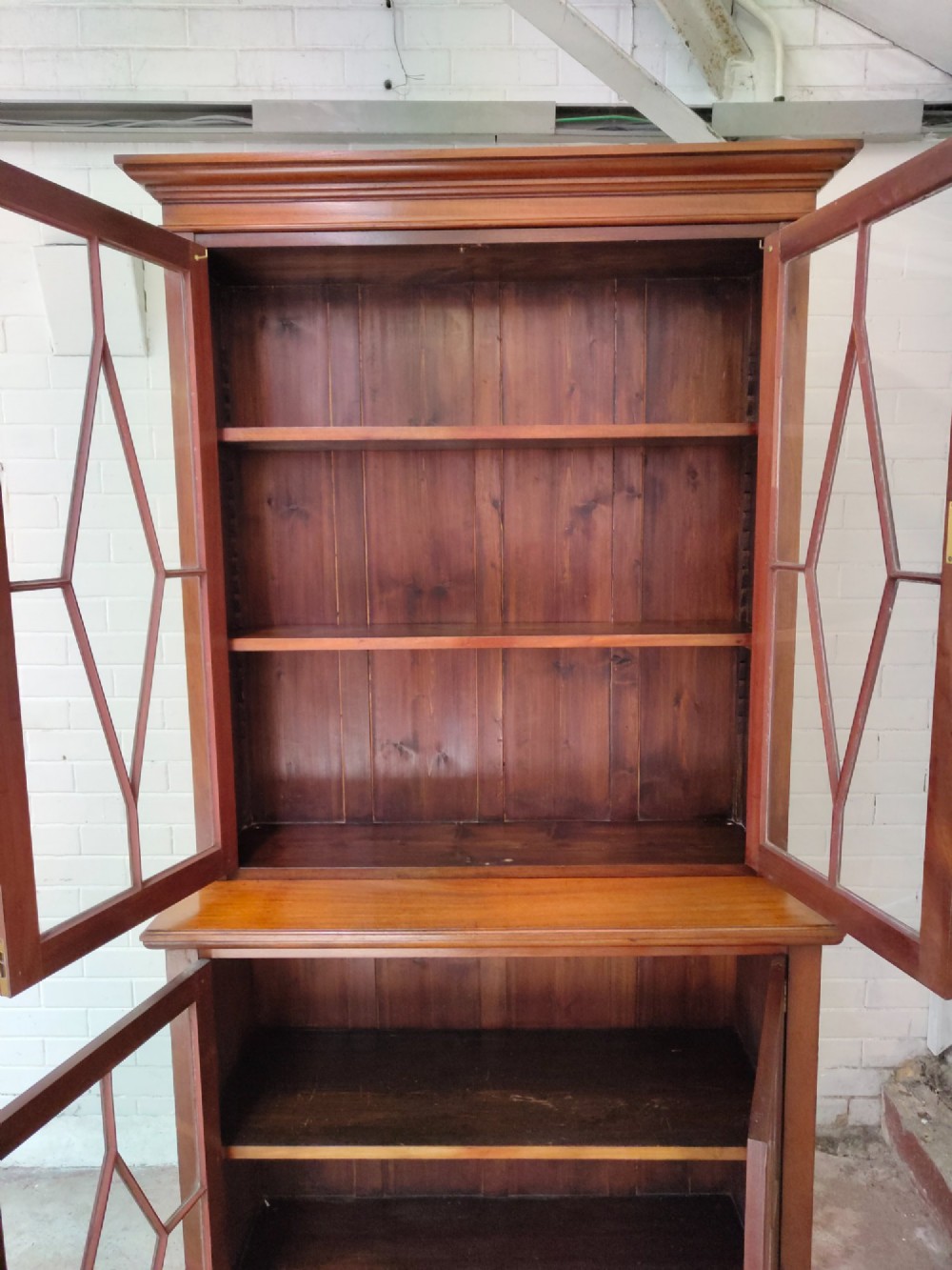 A tall Victorian mahogany bookcase featuring upper and lower double doors with diamond astragal glazed panels and adjustable interior shelves. View IX