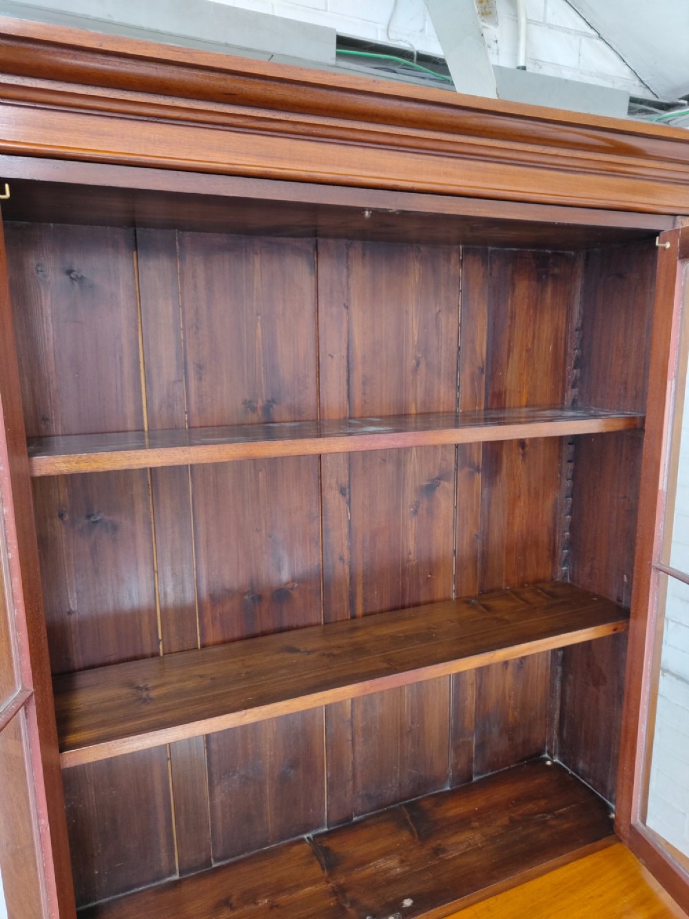 A tall Victorian mahogany bookcase featuring upper and lower double doors with diamond astragal glazed panels and adjustable interior shelves. View X