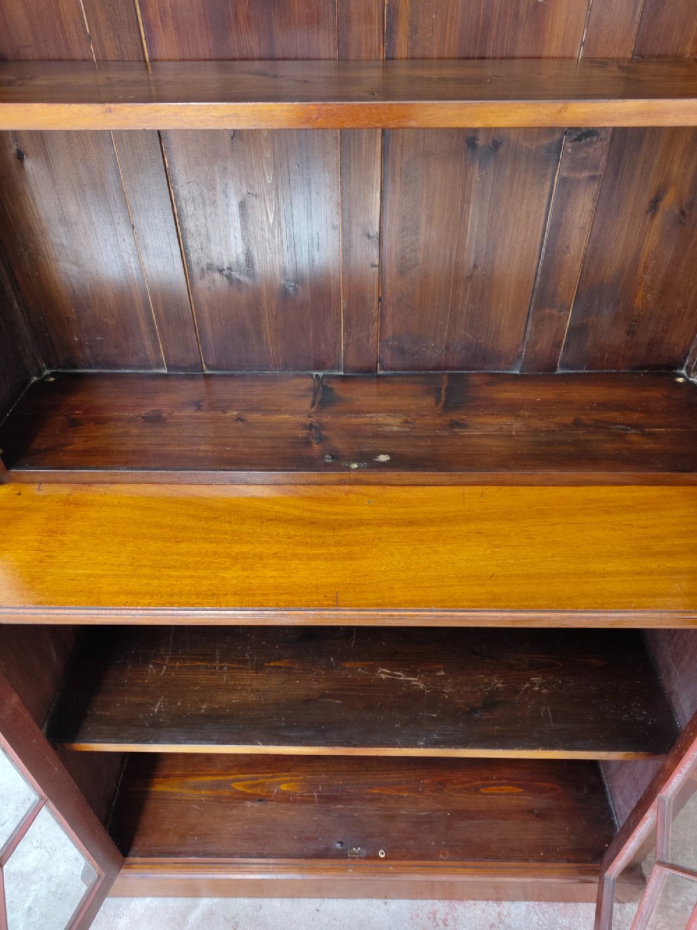 A tall Victorian mahogany bookcase featuring upper and lower double doors with diamond astragal glazed panels and adjustable interior shelves. View XII