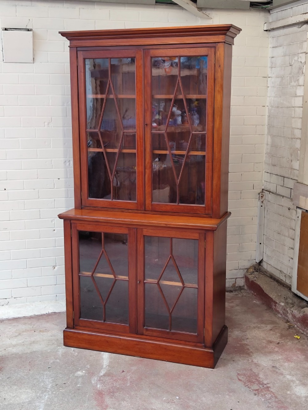 A tall Victorian mahogany bookcase featuring upper and lower double doors with diamond astragal glazed panels and adjustable interior shelves. View XIII