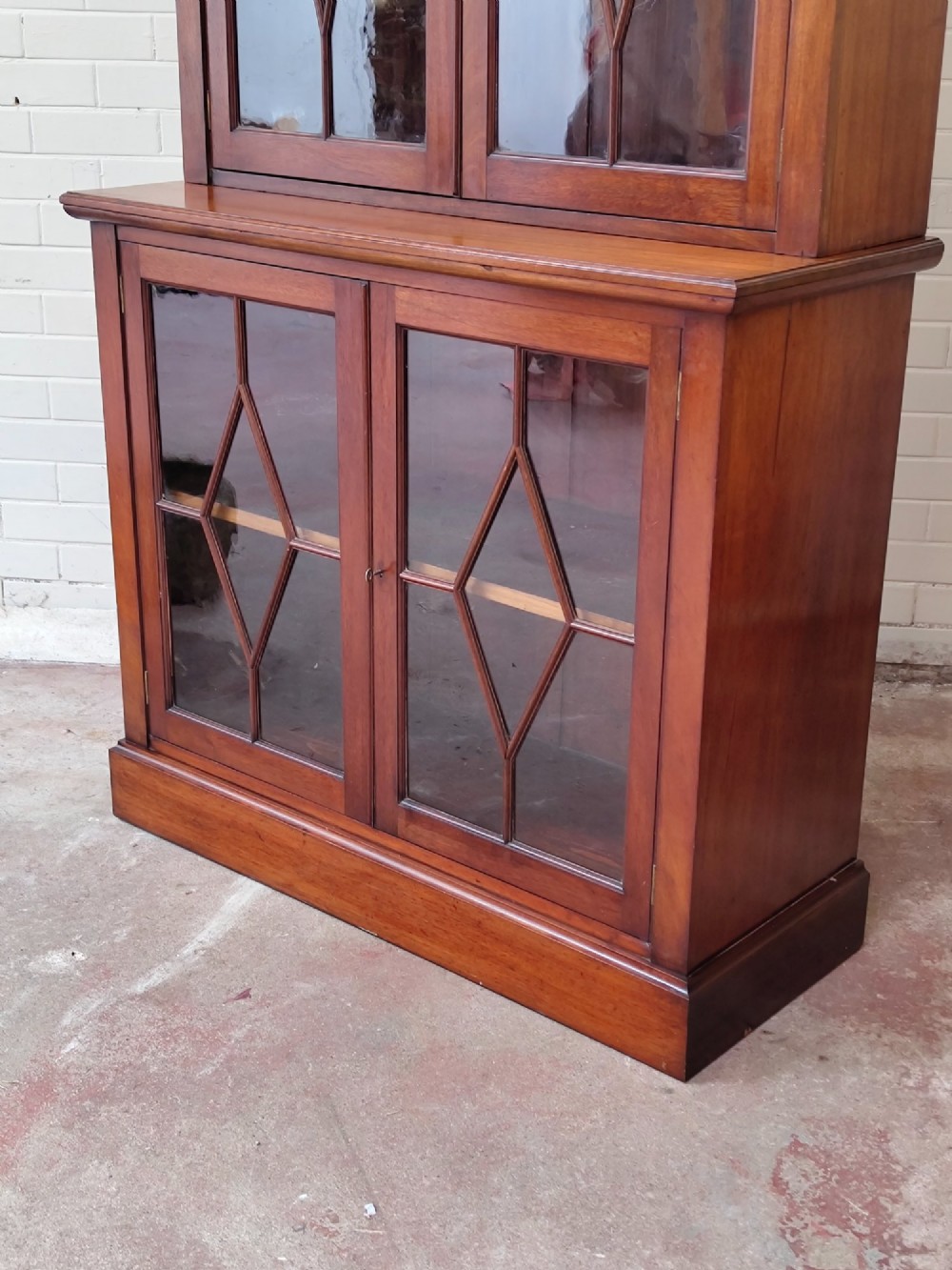 A tall Victorian mahogany bookcase featuring upper and lower double doors with diamond astragal glazed panels and adjustable interior shelves. View XIV