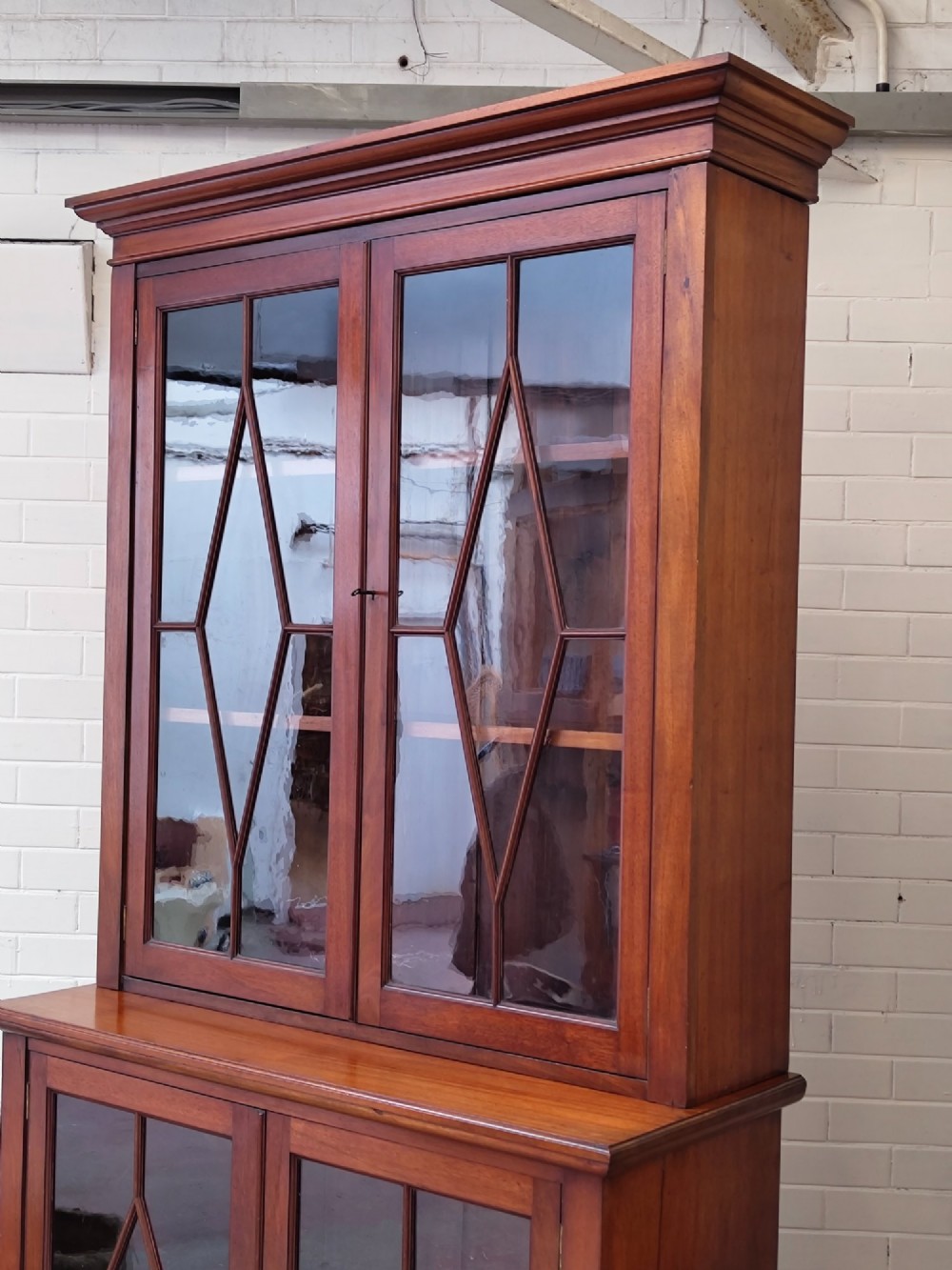 A tall Victorian mahogany bookcase featuring upper and lower double doors with diamond astragal glazed panels and adjustable interior shelves. View XV