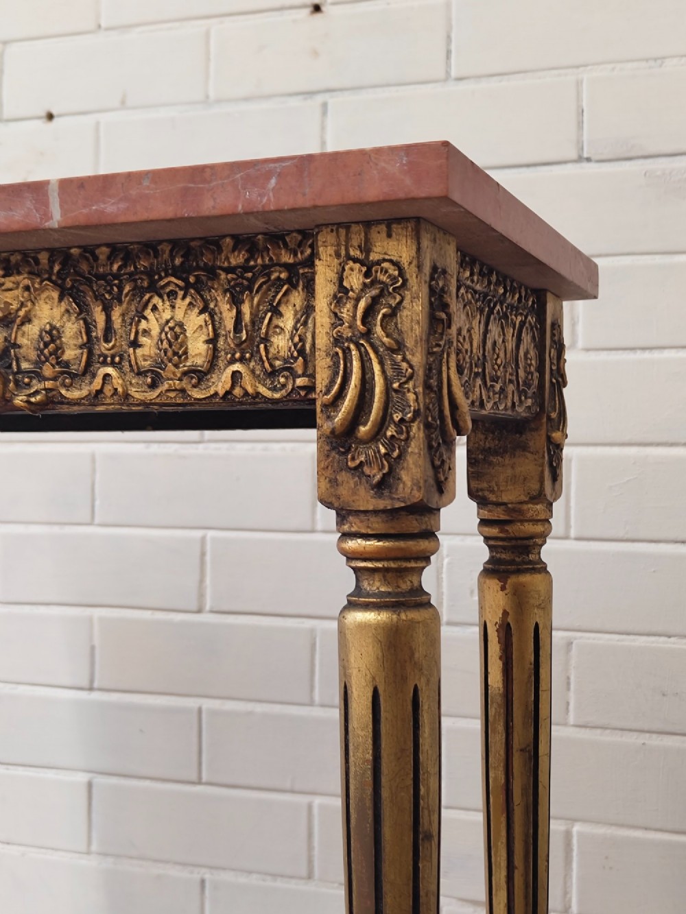 A diminutive French Louis XVI style giltwood console table with a red veined marble top, carved frieze, and slender tapered fluted legs. View IV