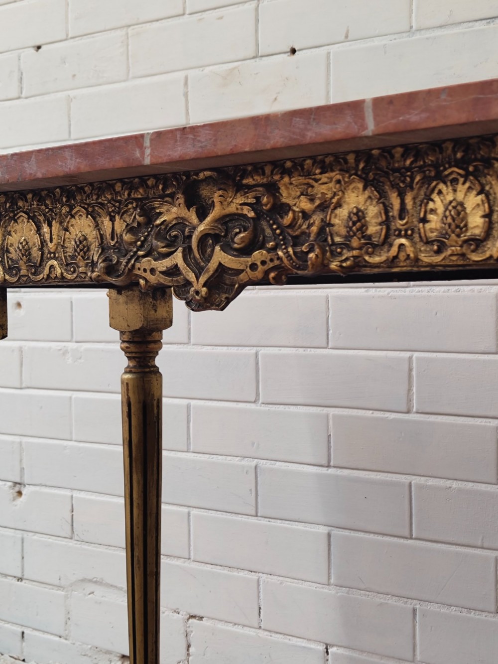 A diminutive French Louis XVI style giltwood console table with a red veined marble top, carved frieze, and slender tapered fluted legs. View V