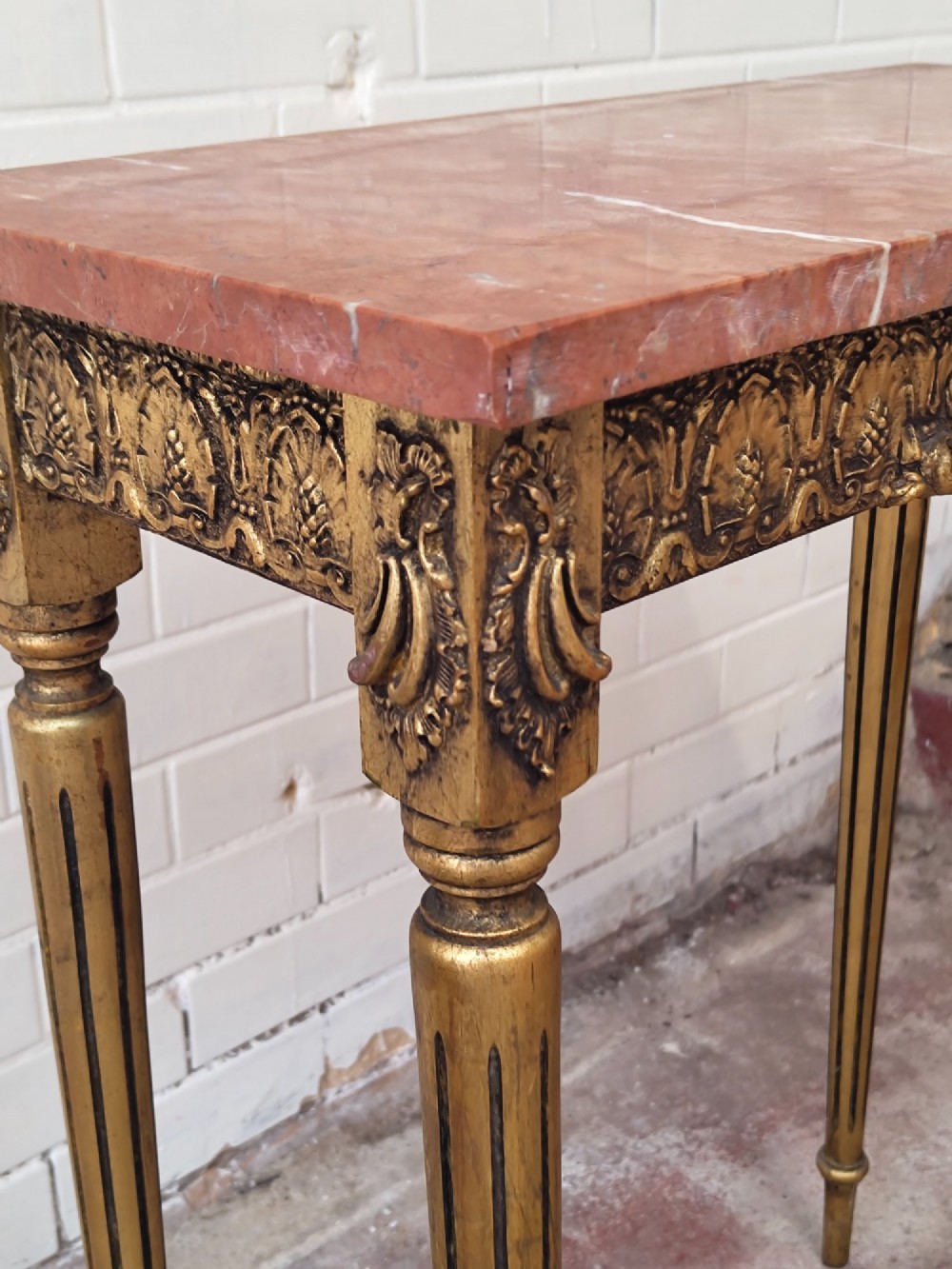 A diminutive French Louis XVI style giltwood console table with a red veined marble top, carved frieze, and slender tapered fluted legs. View VI