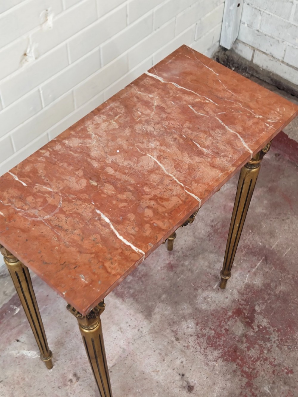 A diminutive French Louis XVI style giltwood console table with a red veined marble top, carved frieze, and slender tapered fluted legs. View VII