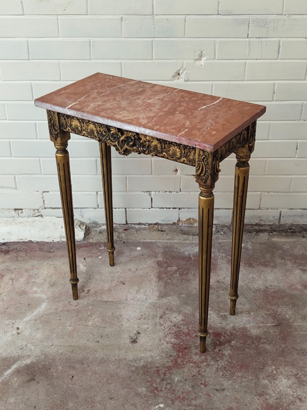 A diminutive French Louis XVI style giltwood console table with a red veined marble top, carved frieze, and slender tapered fluted legs. View XII