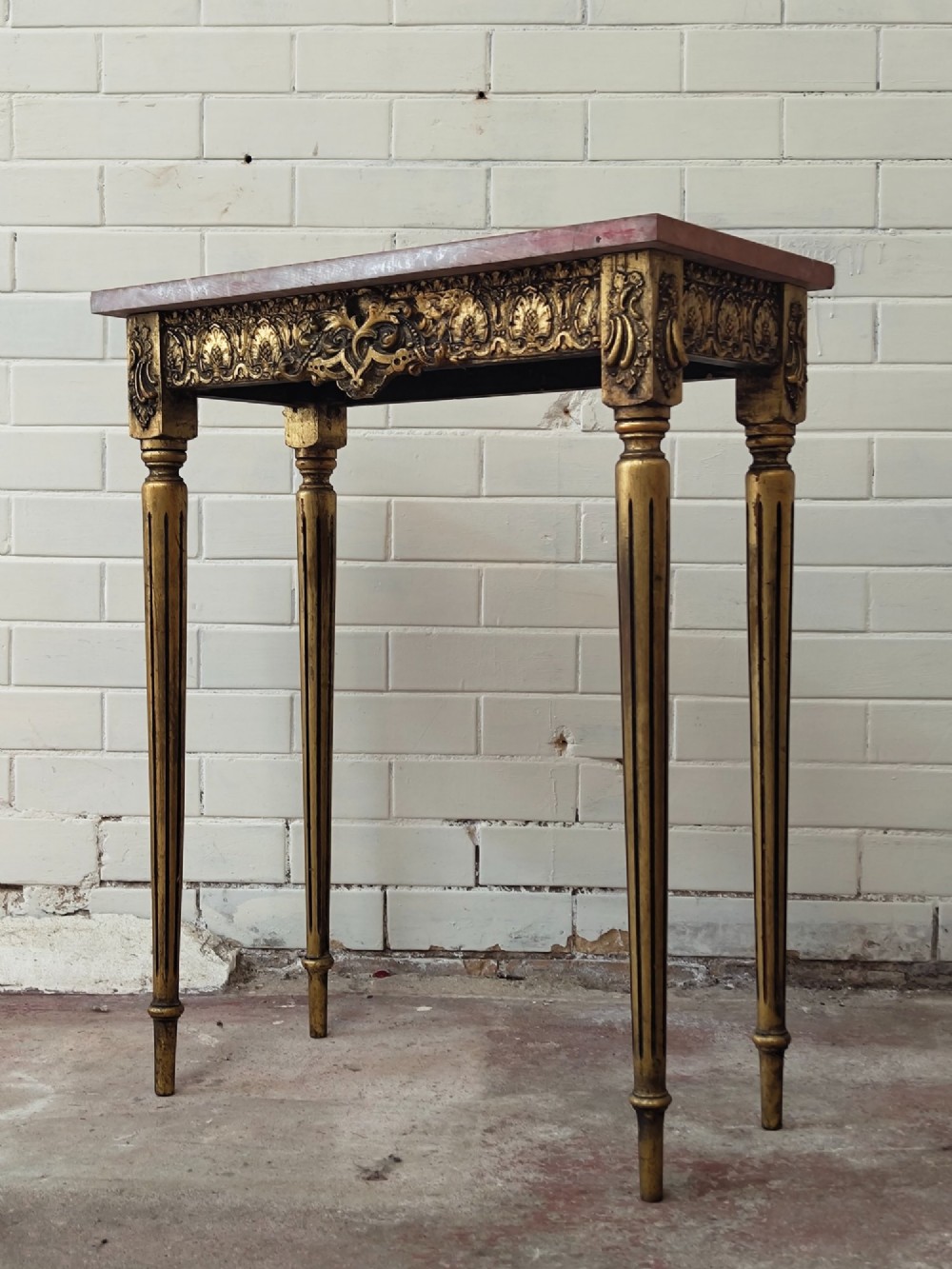 A diminutive French Louis XVI style giltwood console table with a red veined marble top, carved frieze, and slender tapered fluted legs. View XIII