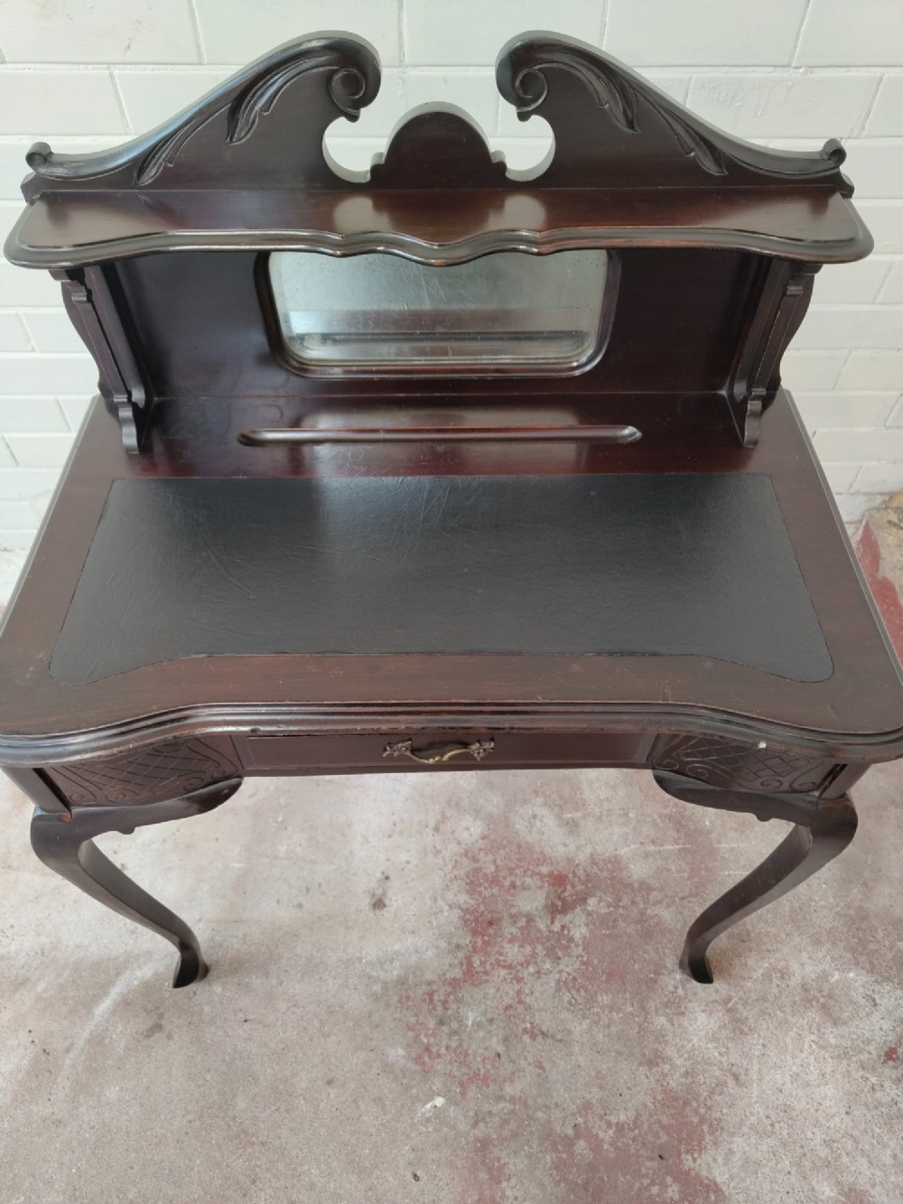 A dark mahogany Victorian ladies writing desk featuring slender cabriole legs, a single drawer, carved lattice details, and a raised back structure with a small central mirror. View VI