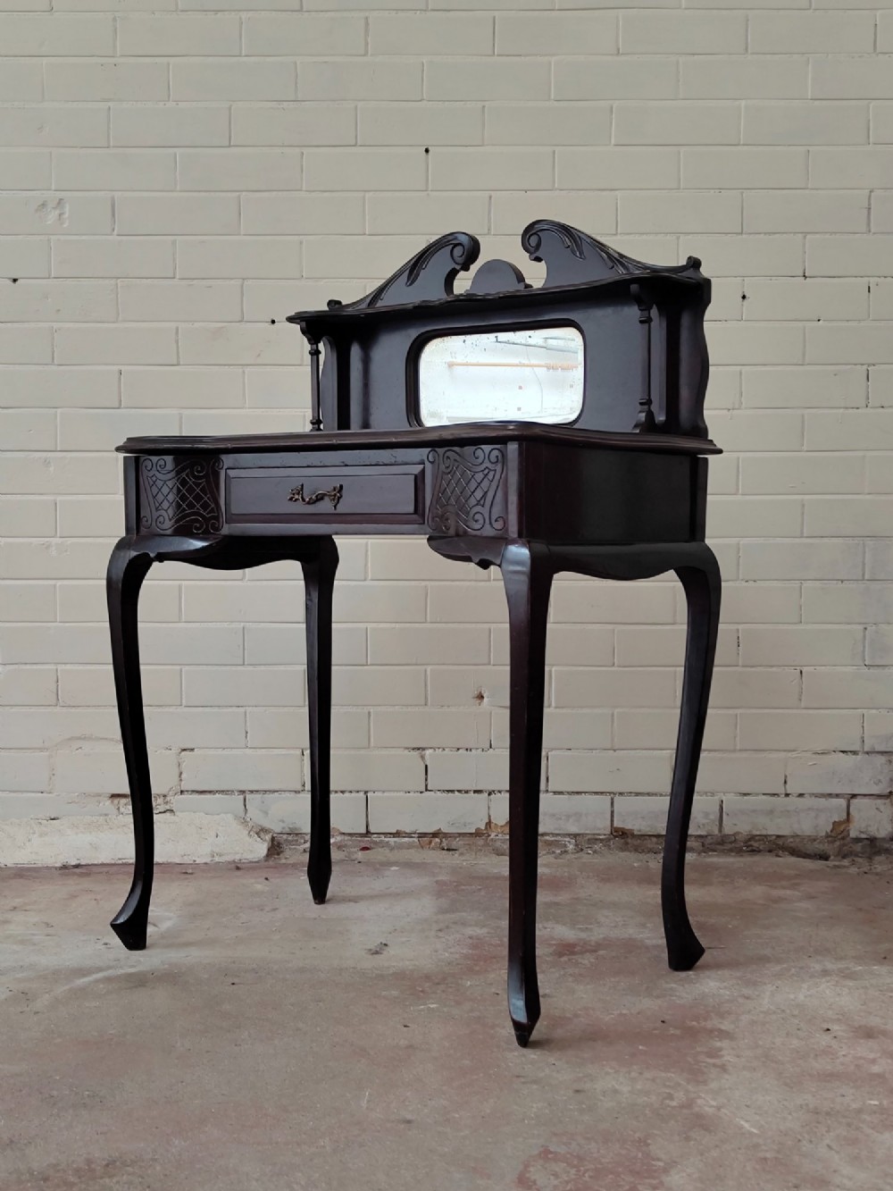 A dark mahogany Victorian ladies writing desk featuring slender cabriole legs, a single drawer, carved lattice details, and a raised back structure with a small central mirror. View XI