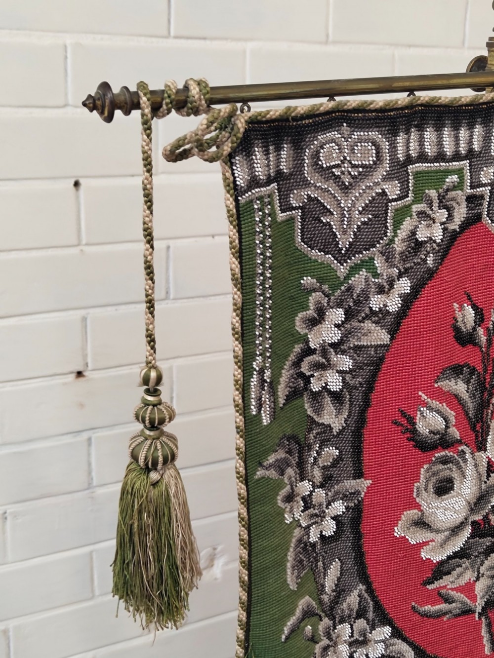 An antique Victorian brass pole screen featuring a green embroidered floral tapestry banner, fringed border, tassels, and a dark green velvet base. View VIII