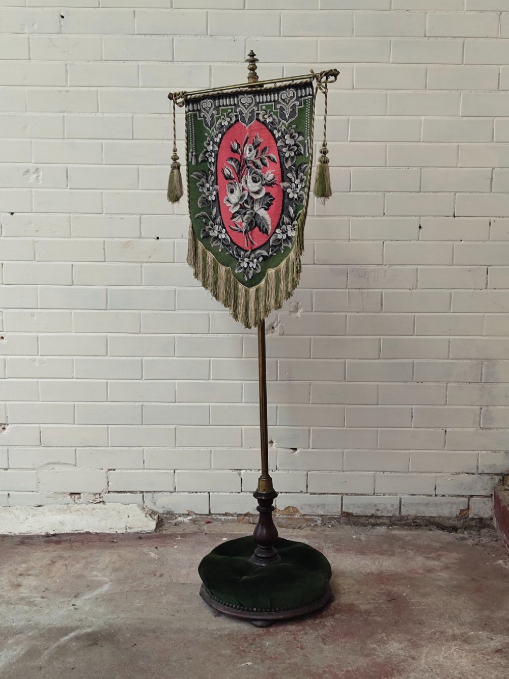 An antique Victorian brass pole screen featuring a green embroidered floral tapestry banner, fringed border, tassels, and a dark green velvet base. View XIV