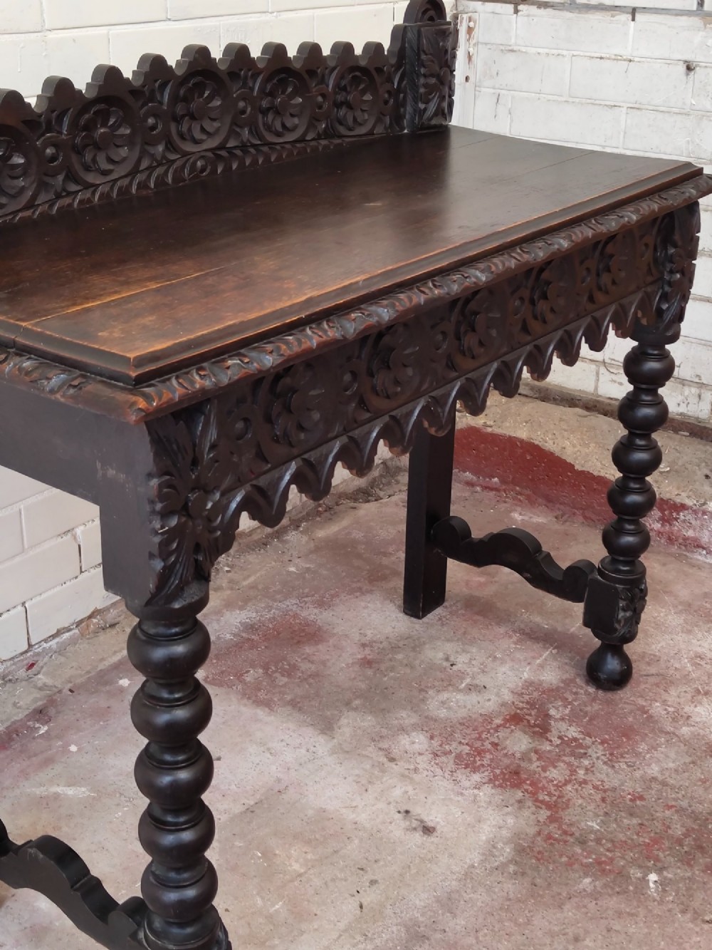 Dark carved oak hall table featuring a carved floral gallery, relief apron, bobbin-turned front legs, and lower stretcher. View V
