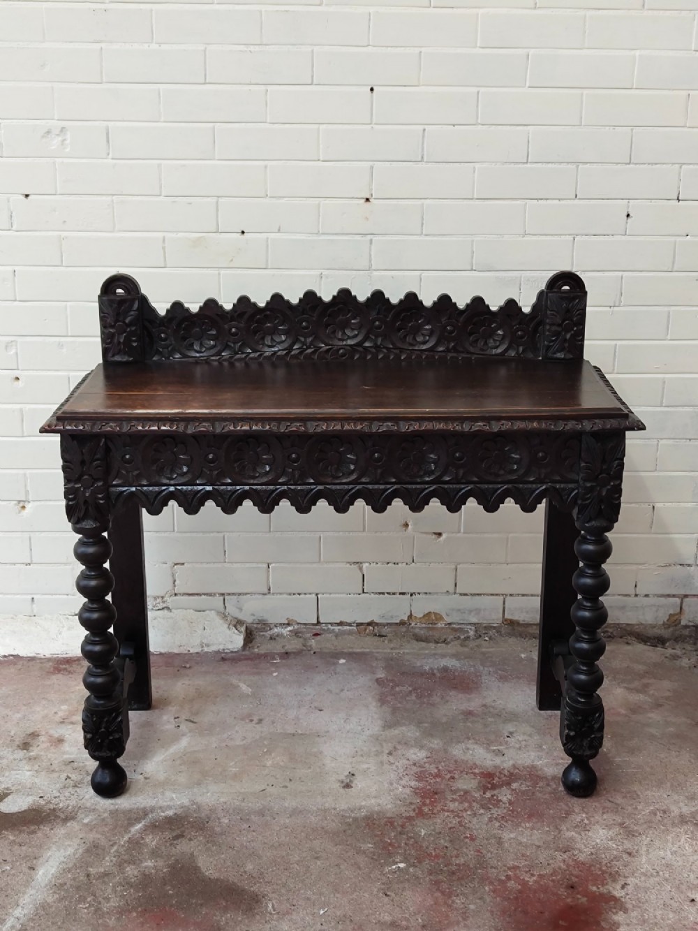 Dark carved oak hall table featuring a carved floral gallery, relief apron, bobbin-turned front legs, and lower stretcher. View X